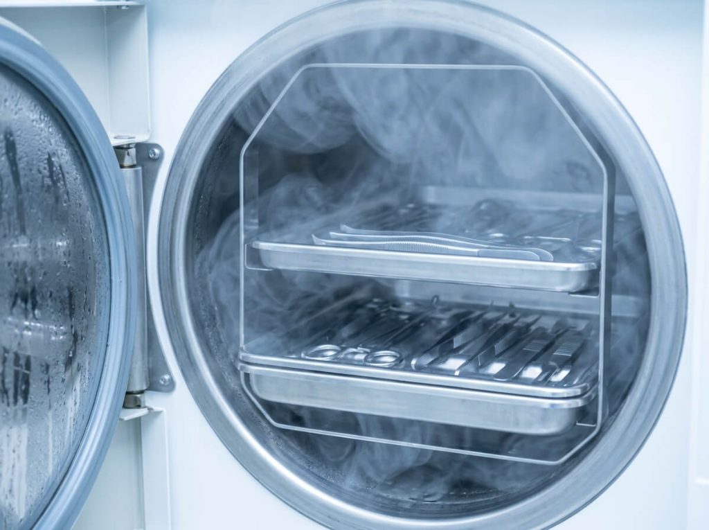 Medical dental instrument trays inside benchtop steam autoclave sterilizer chamber.
