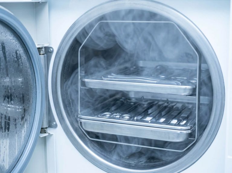 Medical dental instrument trays inside benchtop steam autoclave sterilizer chamber.