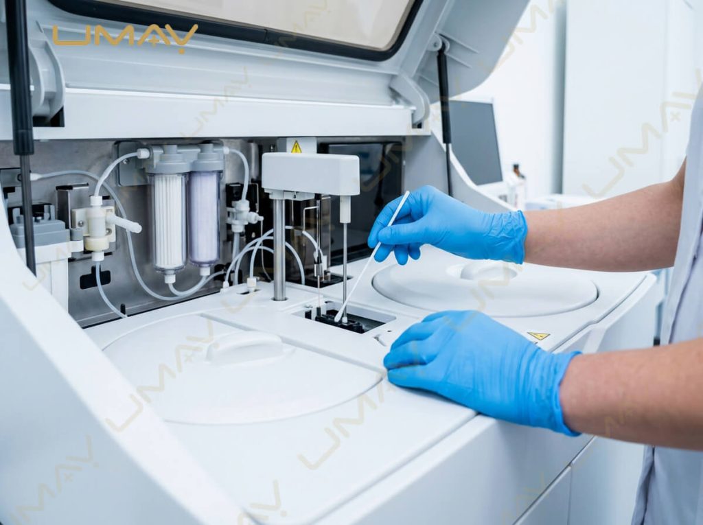 Biomedical technician cleaning reaction cuvettes inside an open automated biochemistry analyzer.