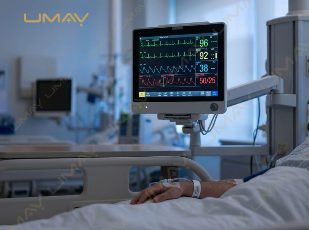 High-resolution ICU patient monitor displaying vital signs waveforms next to a hospital bed.